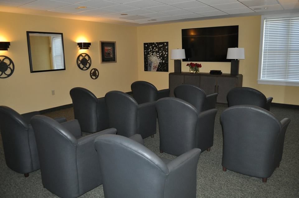 A cozy home theater room with rows of comfortable seating facing a large television screen.