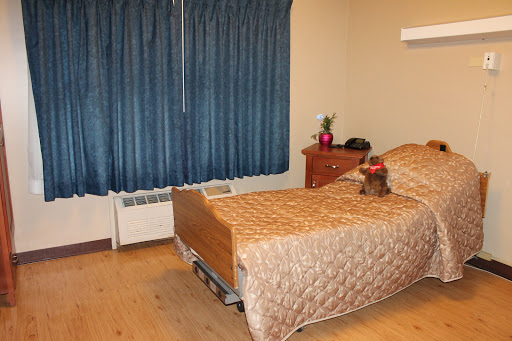 A cozy bedroom featuring a neatly made bed, a wooden nightstand, and blue curtains.