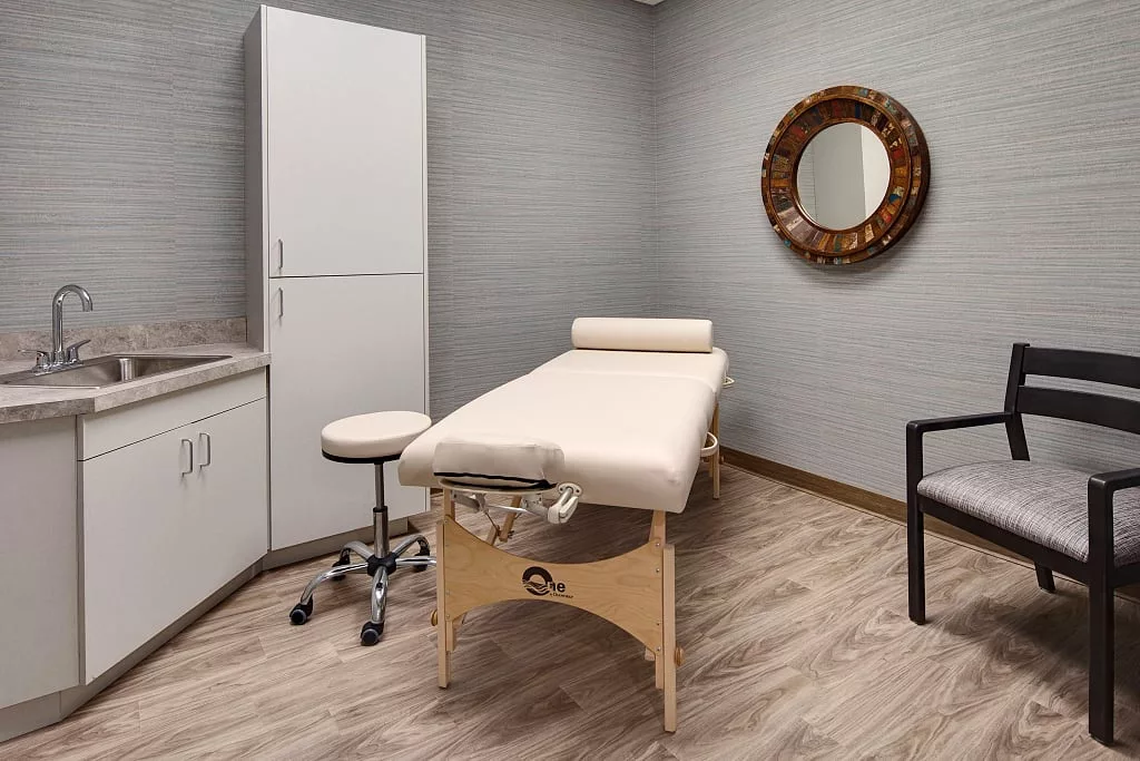 A professional treatment room featuring a massage table and neutral decor.