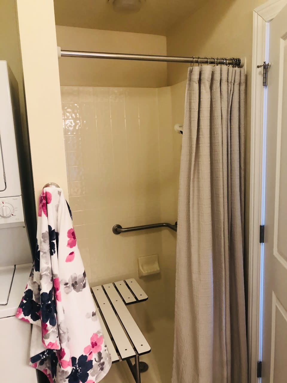 An accessible bathroom with a shower, grab bar, and folding seat.