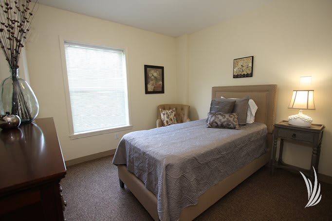 A minimalist bedroom with a single bed, chair, and window.