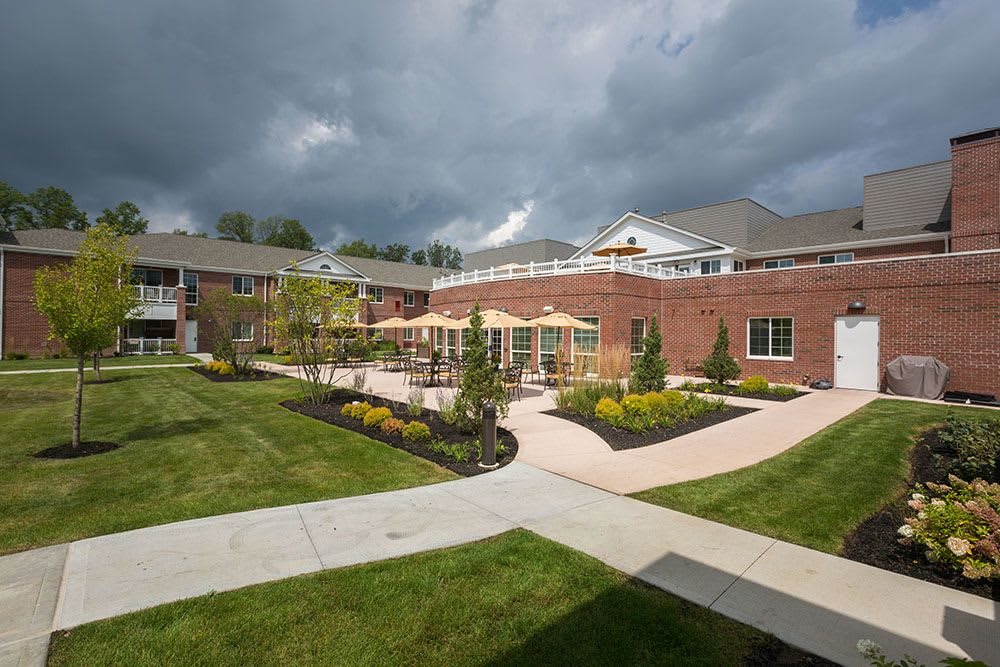 A courtyard with well-maintained landscaping, surrounded by a brick building under an overcast sky.
