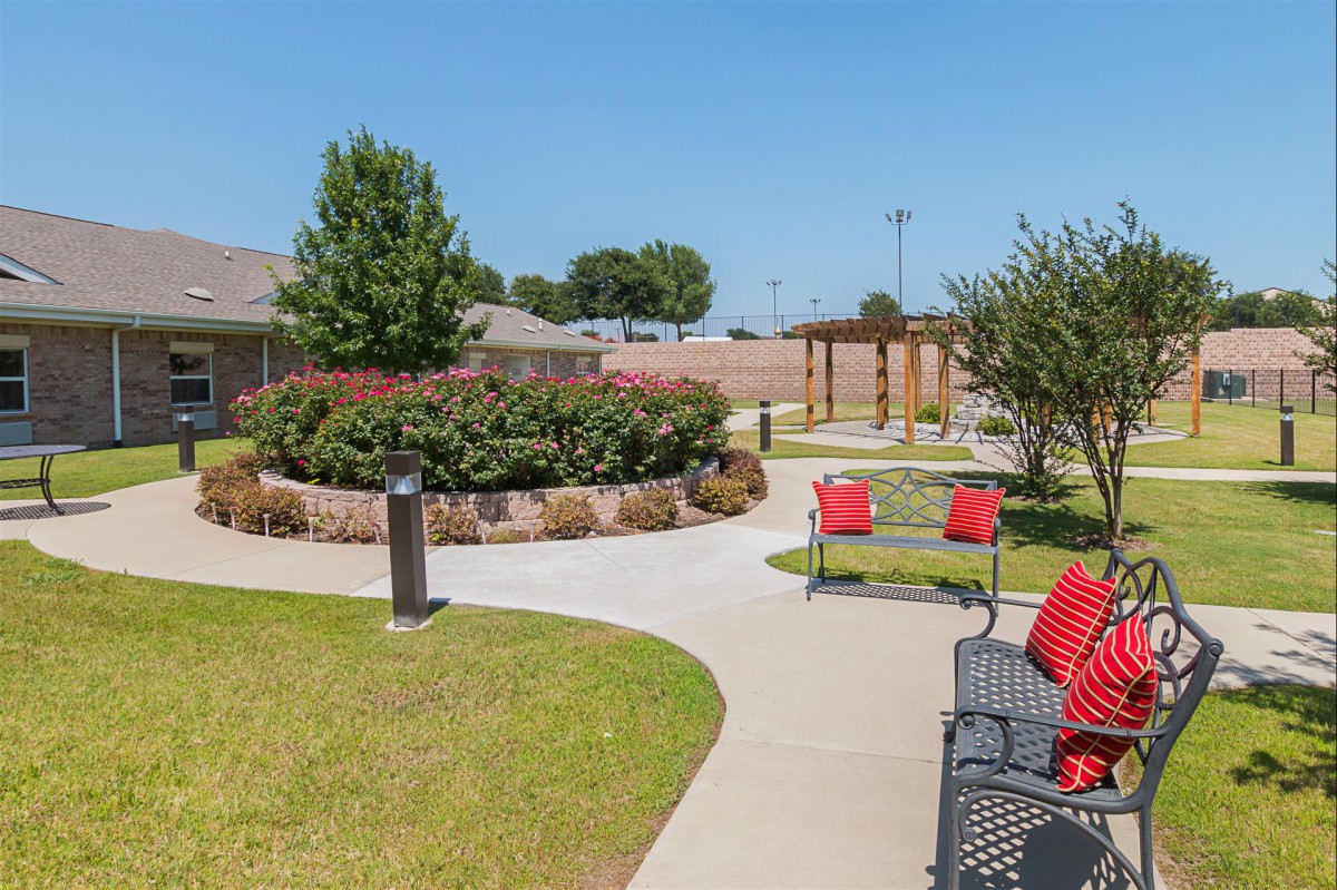 A beautifully landscaped garden with benches and a winding pathway on a sunny day.