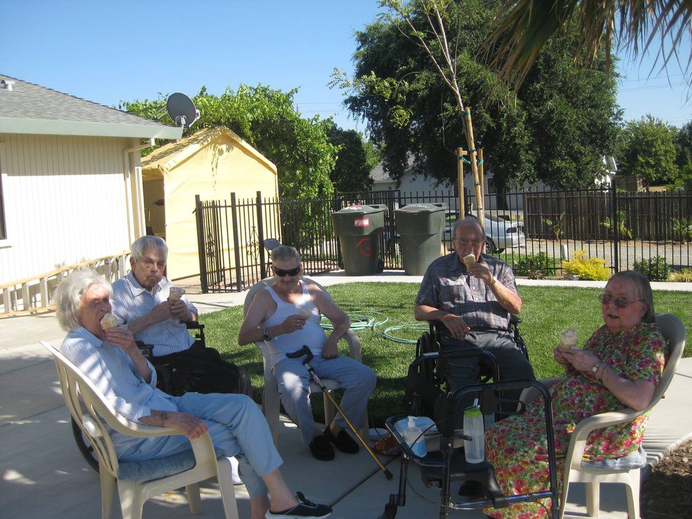A group of elderly people sitting outside and socializing on a sunny day.