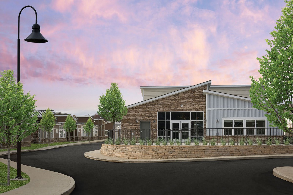A modern school building with a brick facade and well-maintained landscaping under a colorful sky.