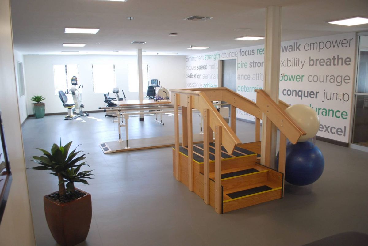 A spacious rehabilitation center equipped with exercise machines and a small staircase for physical therapy exercises.