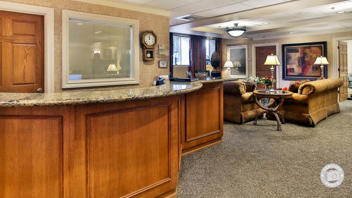 An elegant reception area with a wooden desk and comfortable seating.