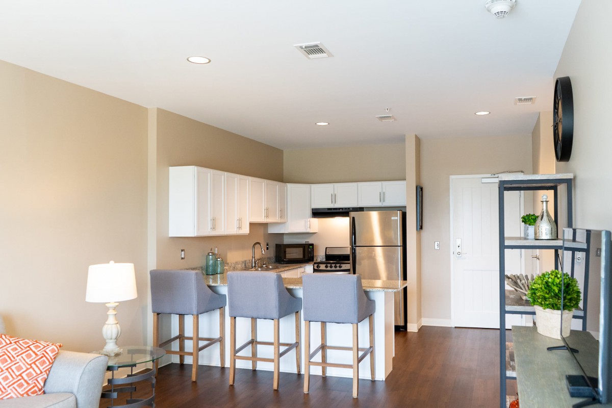 Modern apartment kitchen with stainless steel appliances and a breakfast bar with seating.