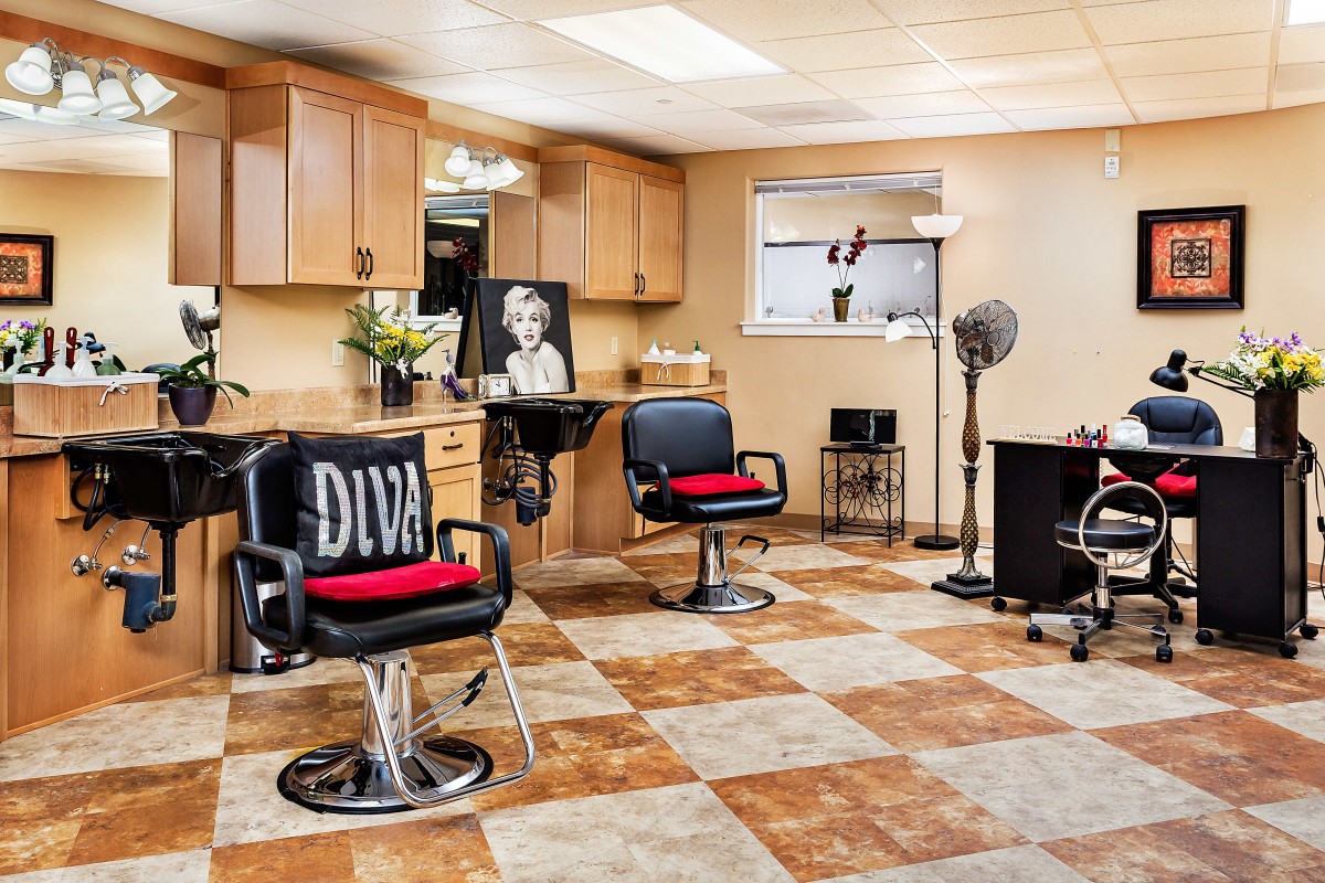 A stylish hair salon interior with black and red chairs, mirrors, and a checkered floor design.