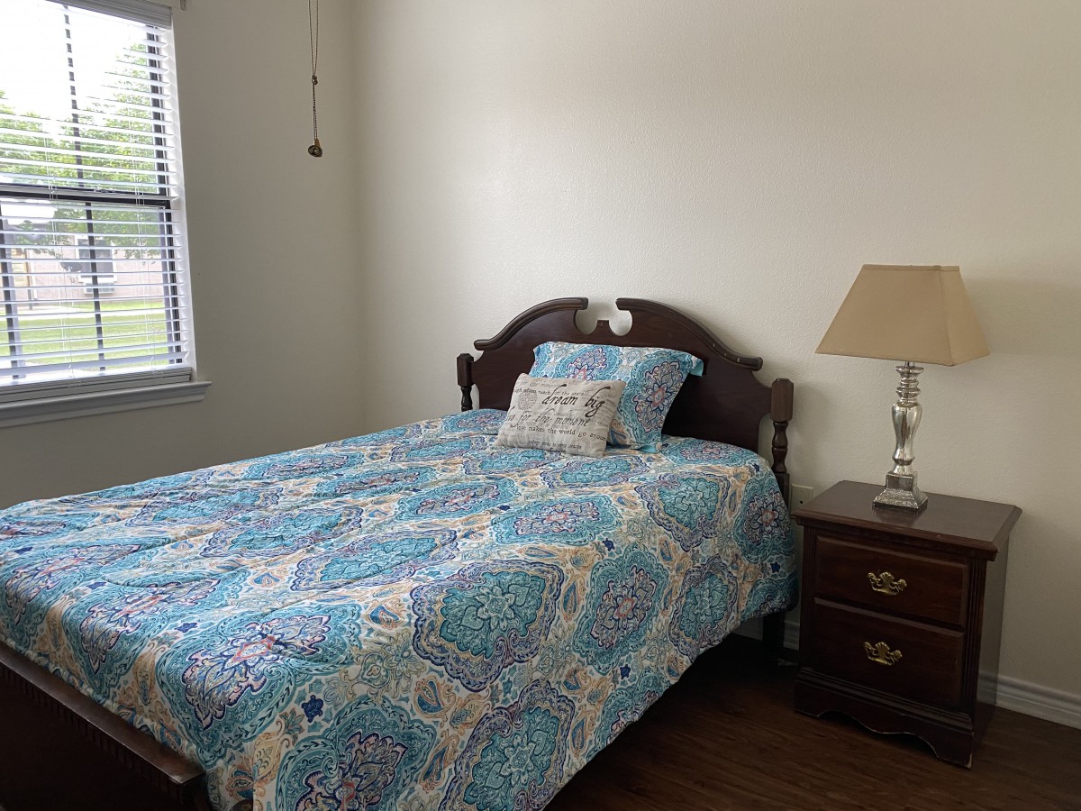 A cozy bedroom with a bed, nightstand, and lamp.