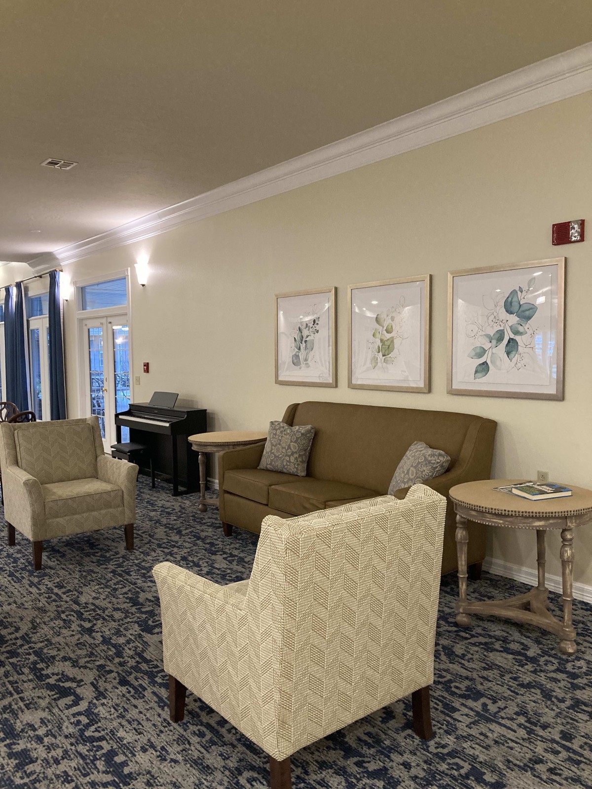 A cozy lounge area featuring a couch and chairs with framed artwork on the walls.