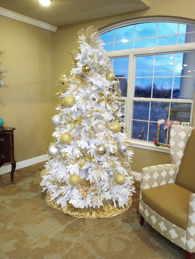 A beautifully decorated white Christmas tree adorned with gold ornaments, creating a warm and festive ambiance.