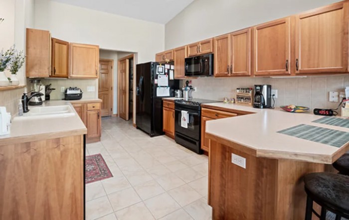 A modern kitchen with wooden cabinets and black appliances.