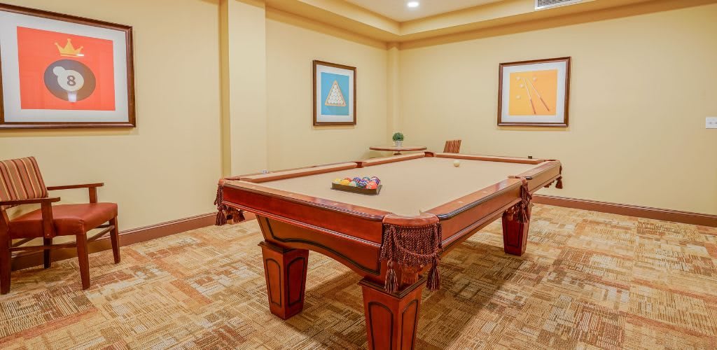 A cozy recreation room featuring a classic pool table with artwork adorning the walls.