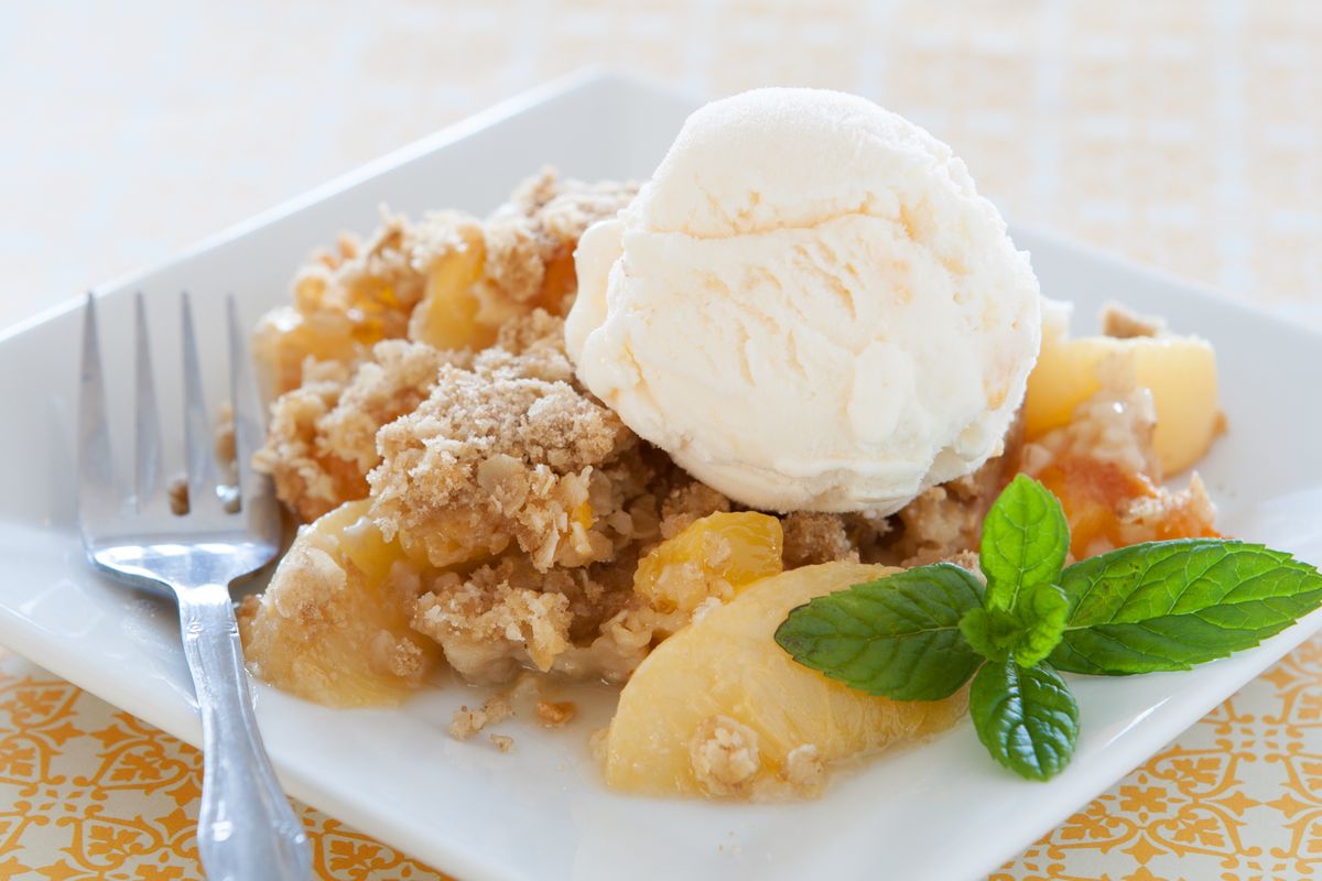 A delicious serving of apple crisp topped with a scoop of vanilla ice cream and garnished with fresh mint.
