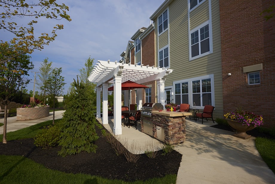 An inviting outdoor patio area with a pergola next to an apartment building, featuring comfortable seating and well-maintained landscaping.