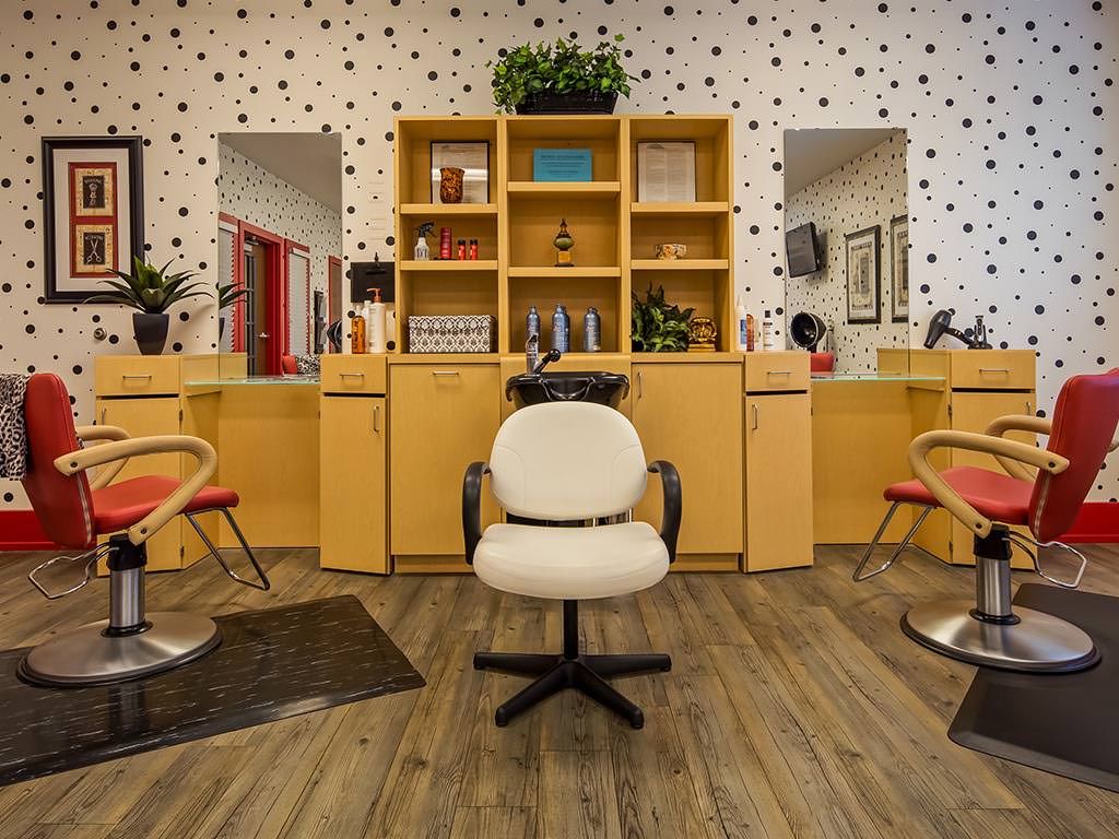 A stylish hair salon interior with modern chairs, large mirrors, and wooden shelving.