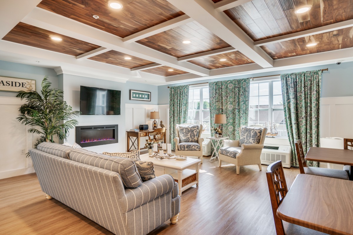 A cozy and stylish living room with a coffered ceiling, comfortable seating, and a modern fireplace.