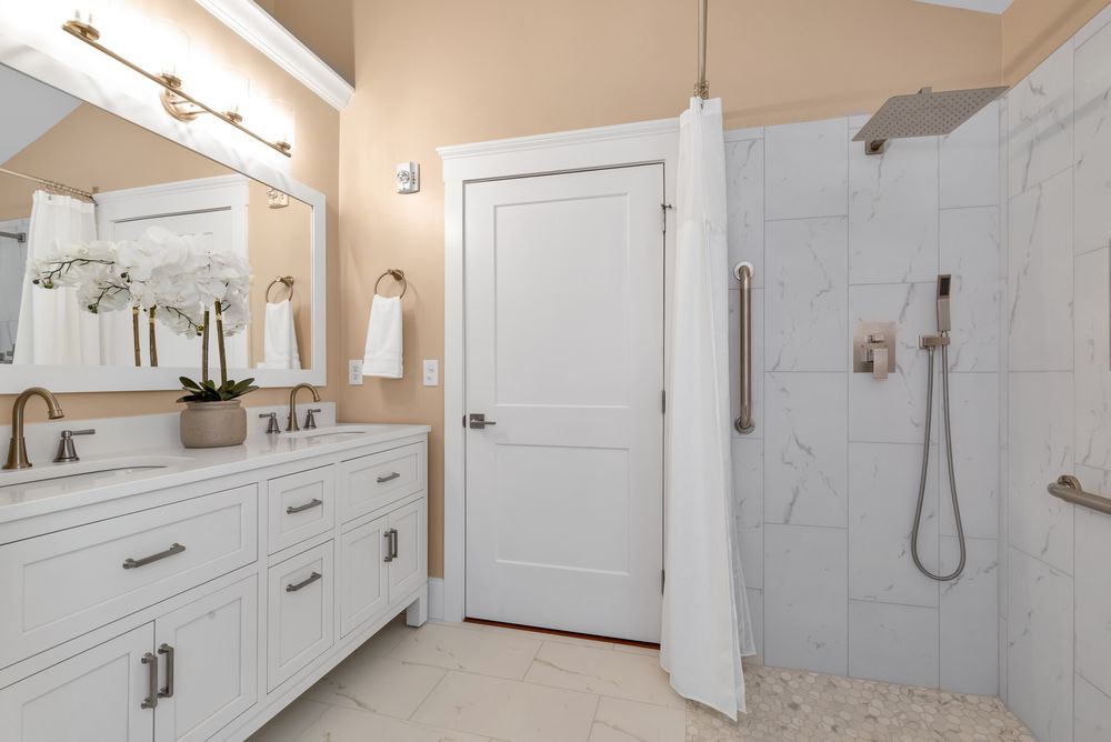 A modern bathroom with a white vanity, mirror, and shower area.