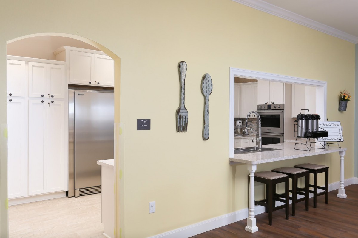 A modern kitchen with open concept design, featuring decorative wall art and stainless steel appliances.