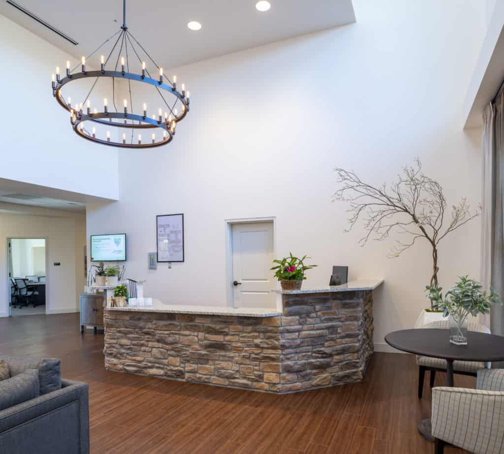 A modern reception area with a stone counter, chandelier, and comfortable seating.