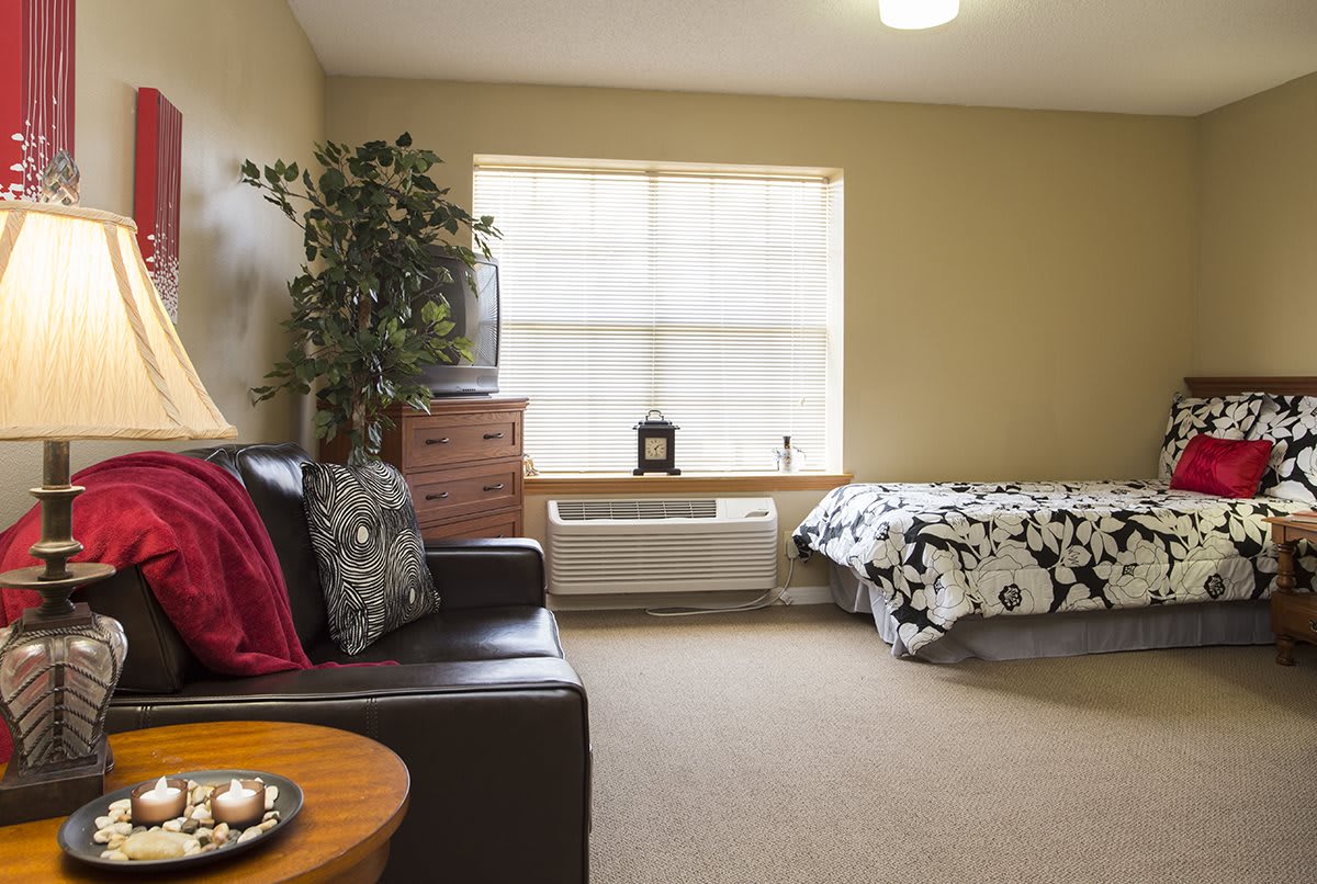 A cozy bedroom with a sofa, bed, and large window providing ample natural light.