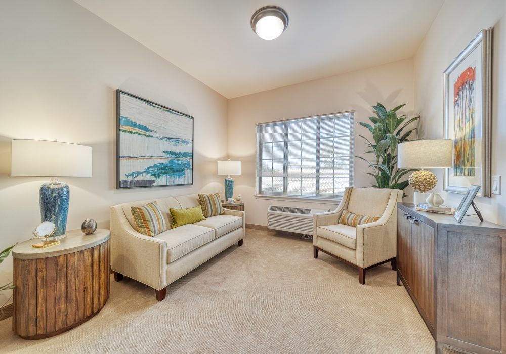 A cozy living room with neutral decor, featuring a sofa, chairs, and soft lighting.