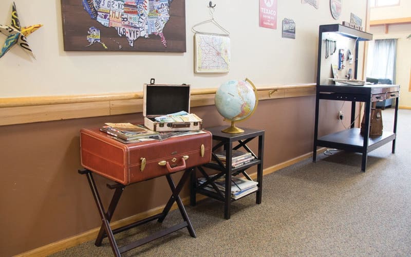 A cozy room corner featuring a record player, globe, and bookshelf with books.