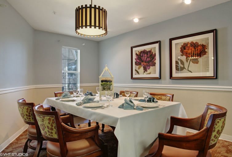 A stylish dining room with a neatly arranged table setting and elegant artwork on the walls.