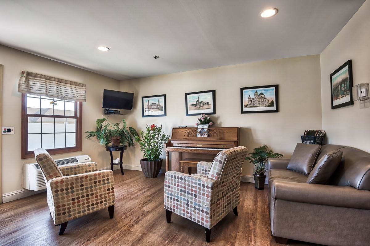 A cozy living room with a piano, comfortable seating, and decorative plants.