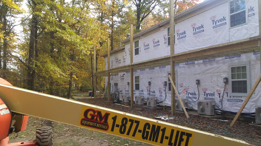 A home under renovation, supported by beams as construction progresses amidst a backdrop of autumn leaves.