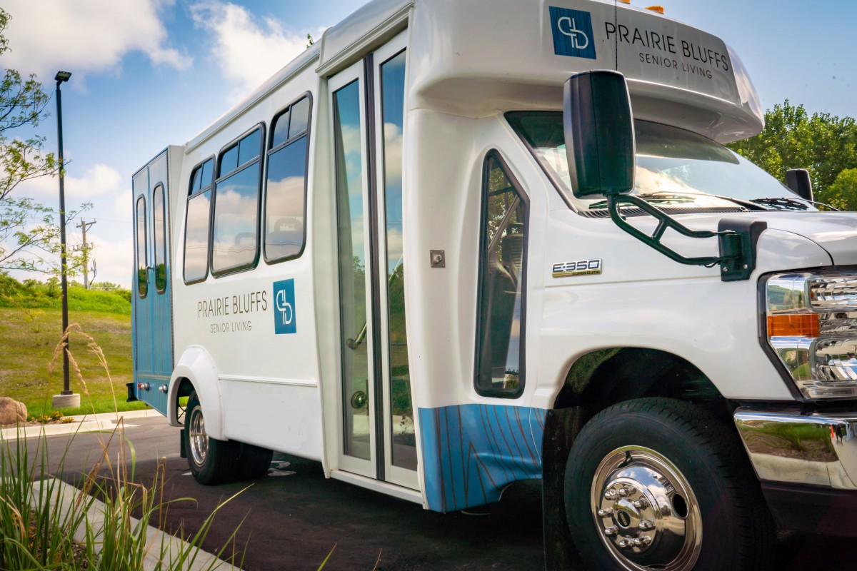 A modern shuttle bus with a blue and white design parked outdoors.