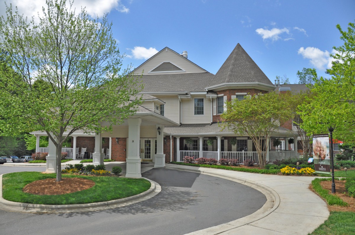 A picturesque residential building with a circular driveway and well-maintained landscaping.