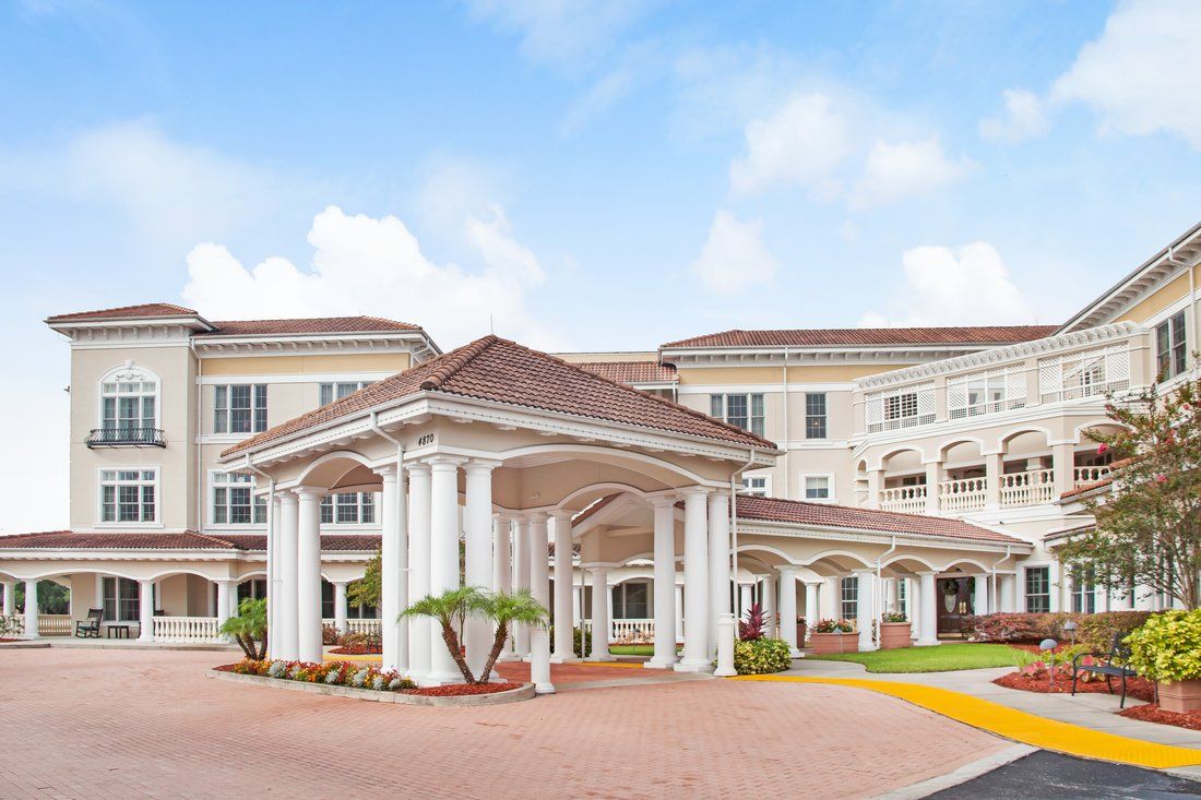 A grand residential building with an elegant columned entrance under a blue sky.