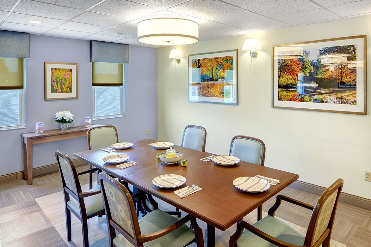 A well-decorated dining room with a wooden table and chairs, featuring wall art and modern lighting.