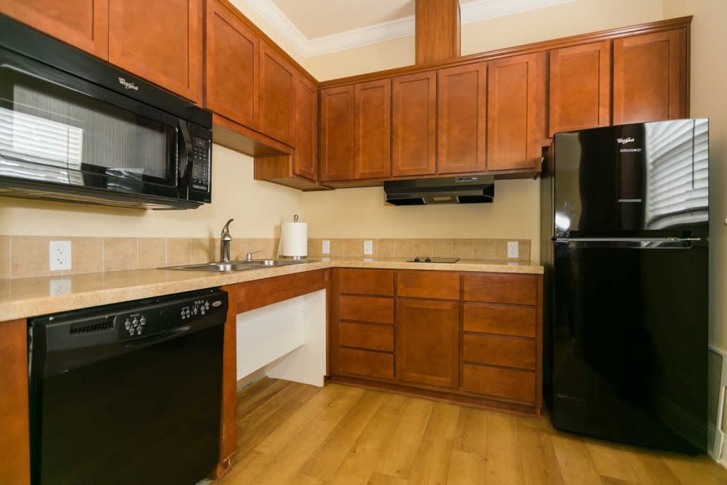 A modern kitchen with wooden cabinets and black appliances.