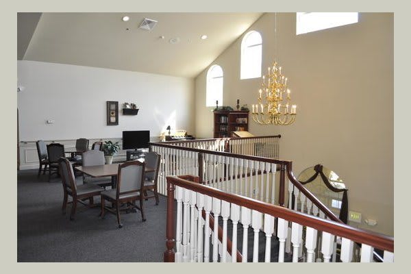 A spacious office interior with a chandelier and elegant wooden railings.
