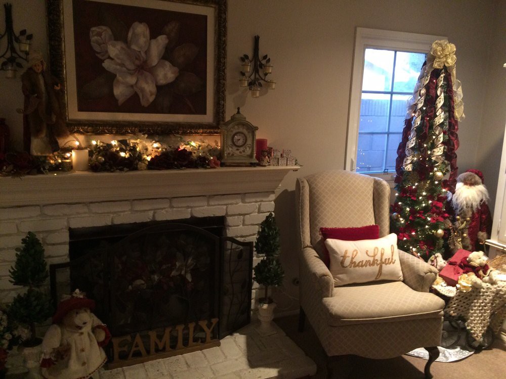 A cozy living room decorated for the holidays, featuring a warm fireplace and a beautifully adorned Christmas tree.