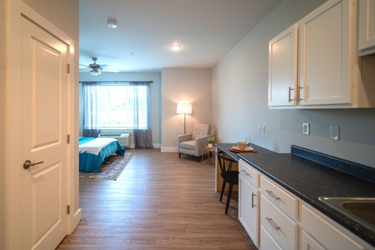 A modern studio apartment with a cozy bedroom, a kitchenette area, and stylish furniture.