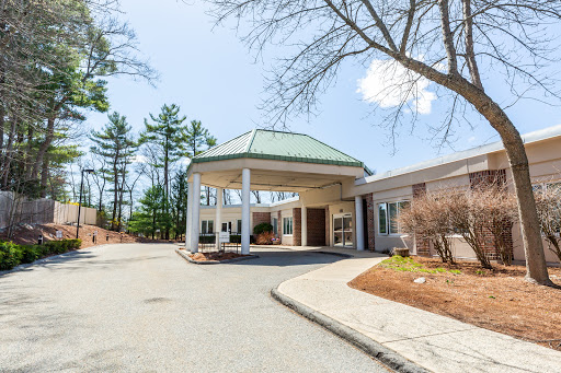 Entrance of a hotel surrounded by trees on a clear day.