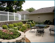 A well-maintained garden with a patio area featuring outdoor furniture and decorative landscaping.