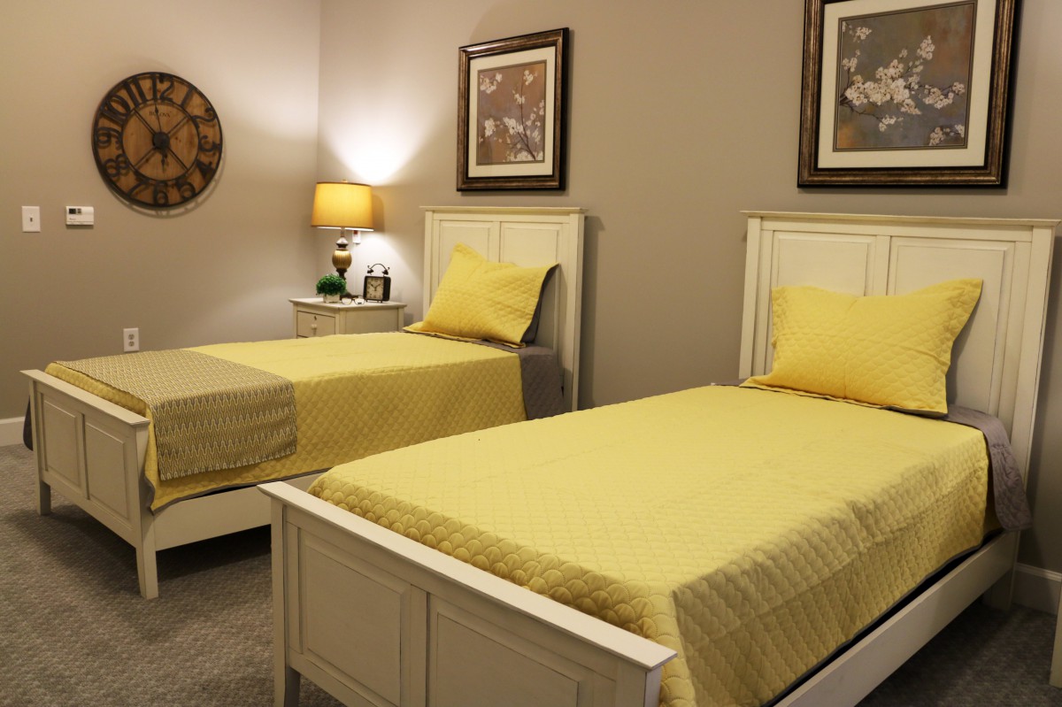 A cozy bedroom featuring twin beds with yellow bedding and stylish decor.