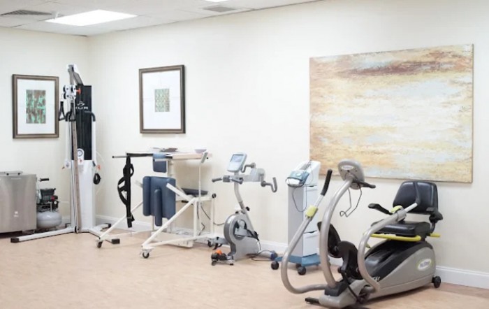 A physical therapy room equipped with stationary bikes and various rehabilitation devices.
