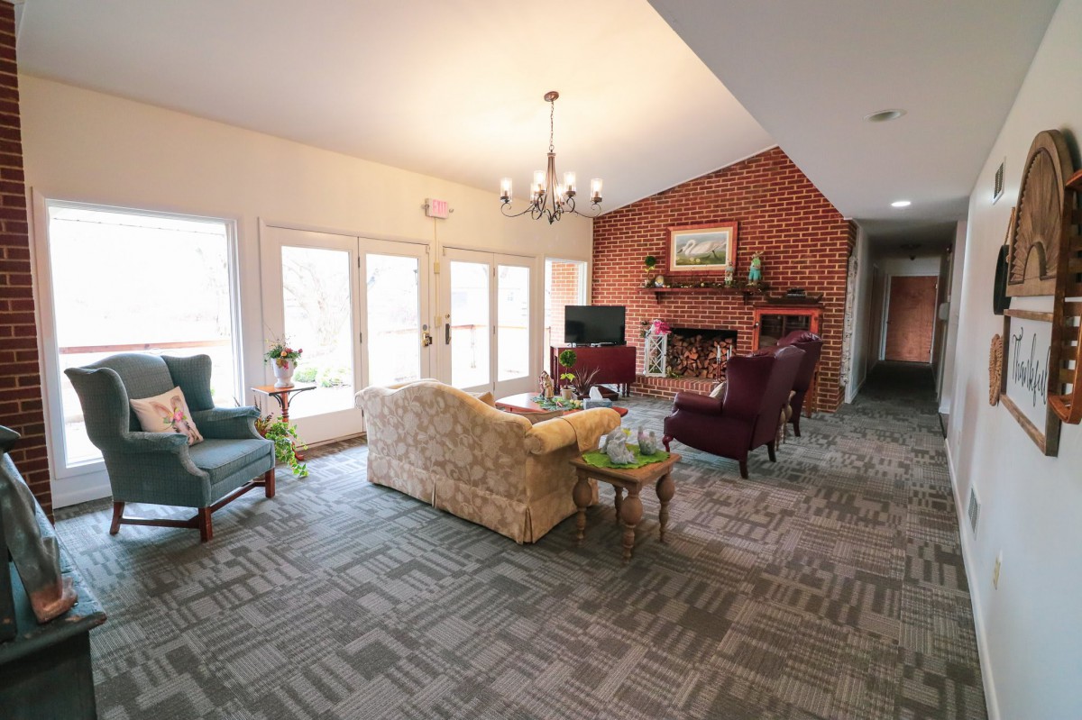 A cozy living room featuring a sofa, armchairs, and a brick fireplace.
