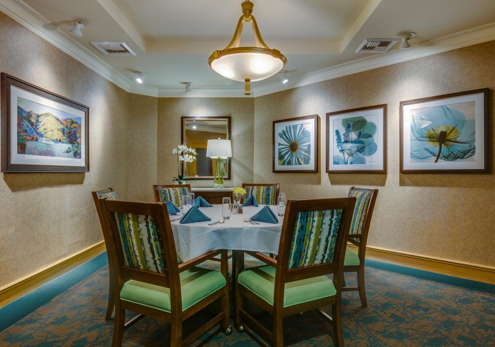 A neatly arranged dining table surrounded by chairs, adorned with elegant decorations and artwork on the walls.