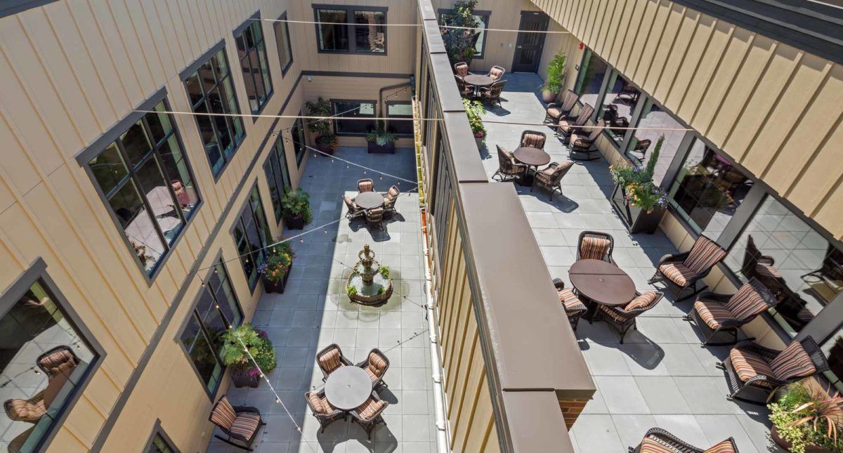 A view of a courtyard with tables, chairs, and a fountain surrounded by plants.