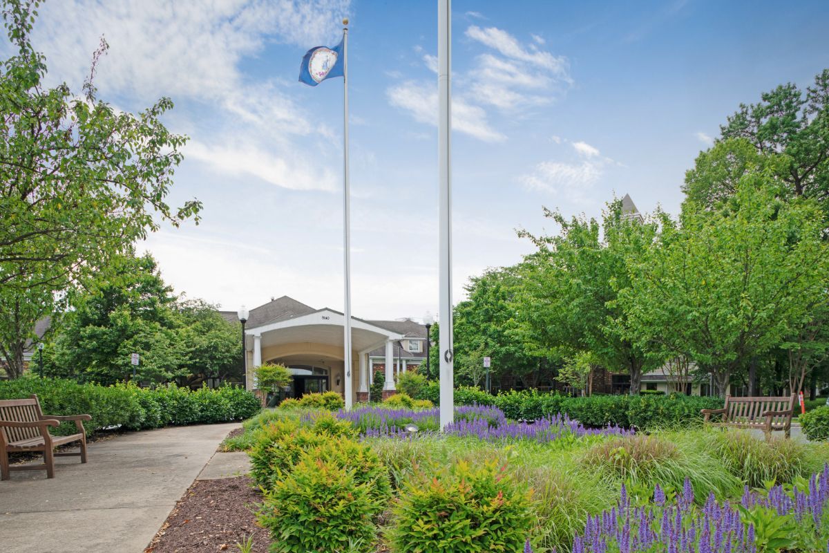 A well-maintained entrance with flags and lush greenery on a clear day.