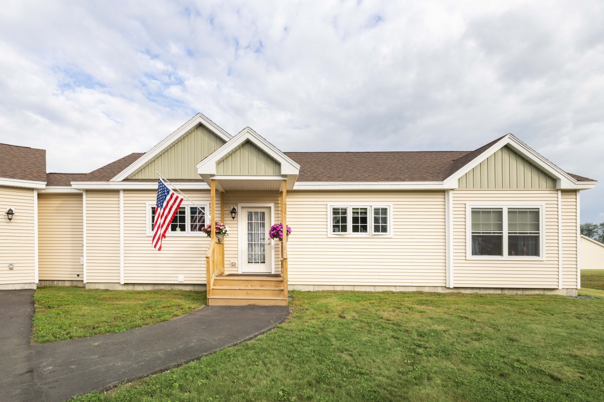 A suburban house with a front porch and an American flag displayed.