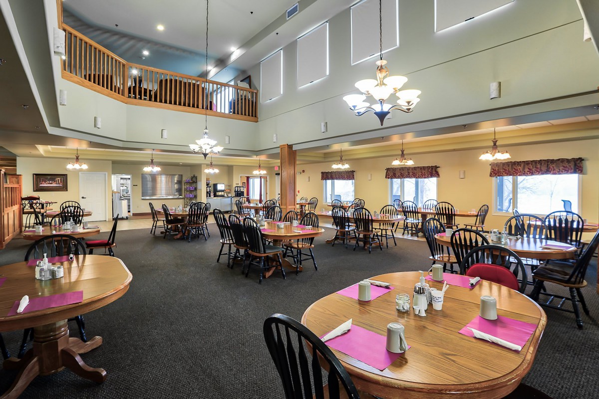 A spacious dining room with neatly arranged tables and warm lighting.