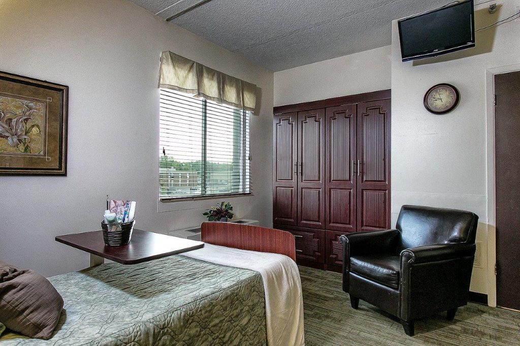 A cozy room with a bed, armchair, and television.